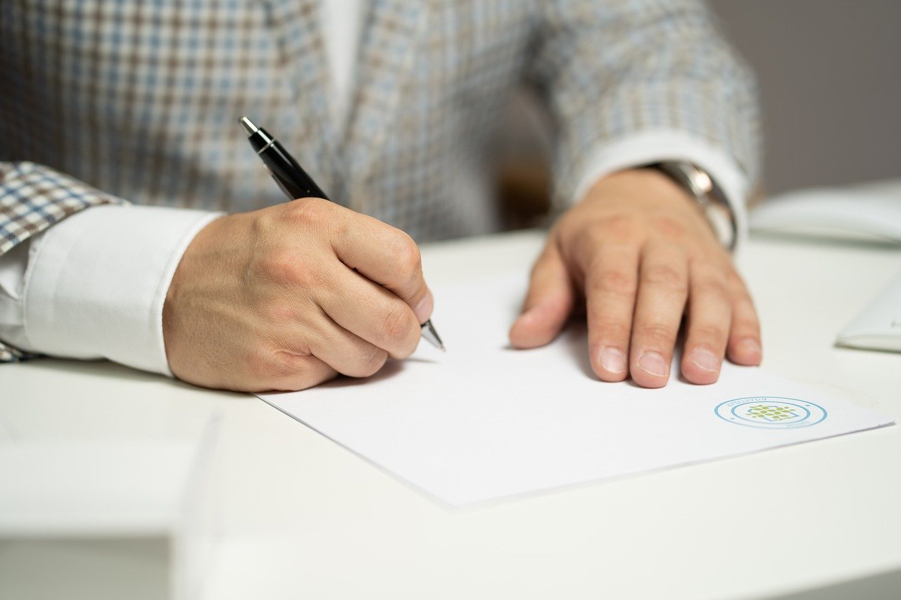 Person in formal attire writing on a document